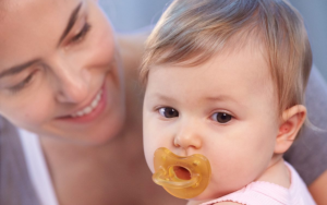 Mother and baby together. Baby has a Chicco latex soother in their mouth.
